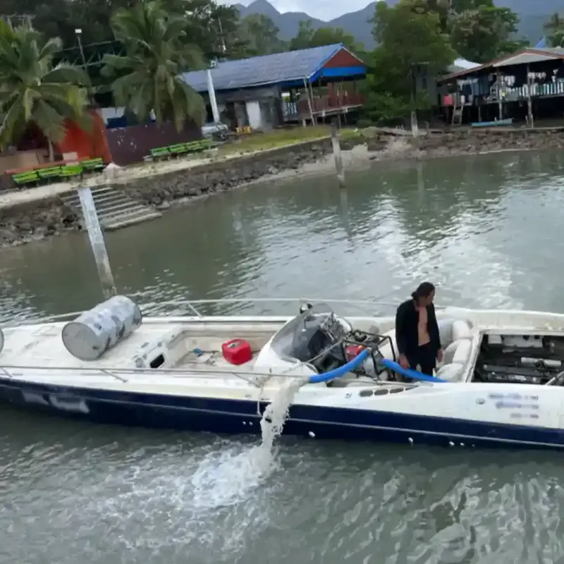 Bateau de plongée amarré avec une personne à bord et des bâtiments