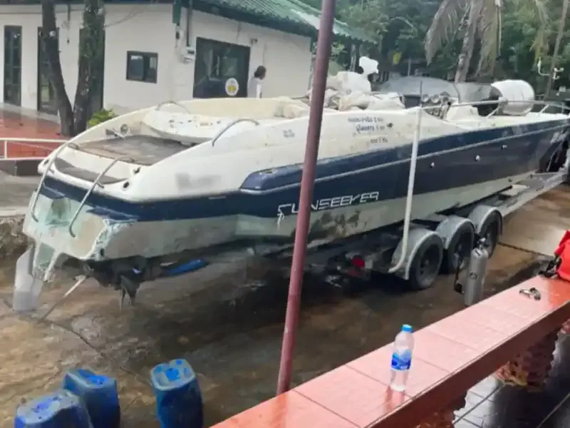 Bateau de plongée sur remorque devant un bâtiment et des arbres