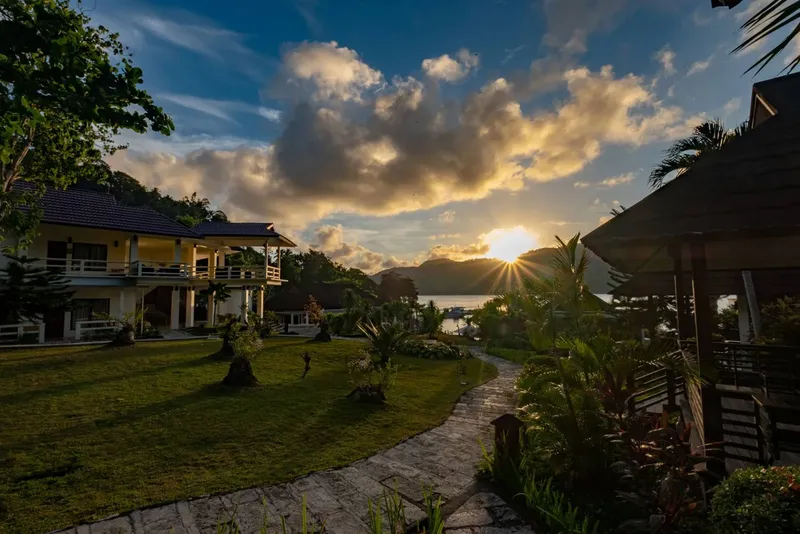 Bâtiments du centre de plongée, pelouse verte, chemin et coucher de soleil