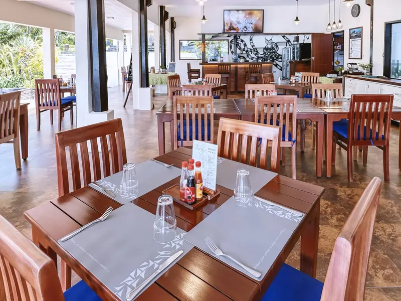 Salle de restaurant lumineuse avec tables en bois et chaises bleues