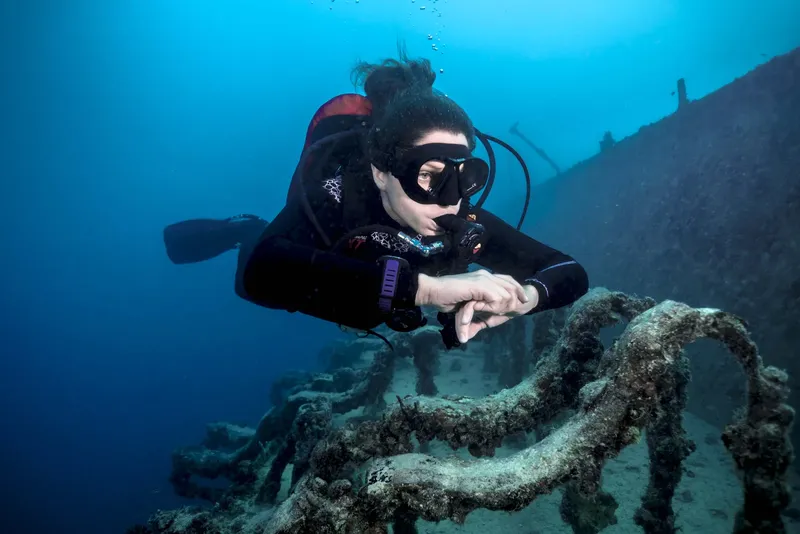 Plongeuse explore un épave sous-marine avec une visibilité claire
