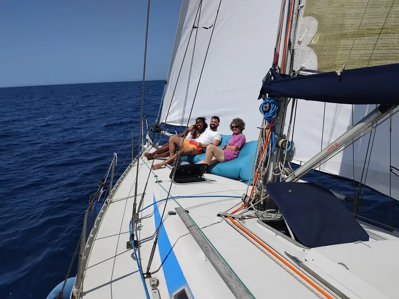 Trois personnes souriantes se reposent sur un voilier en mer