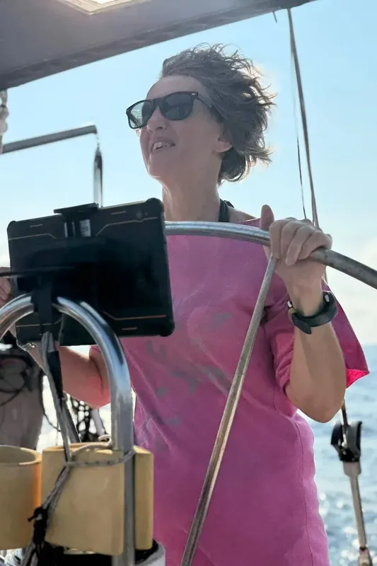 Personne tenant la barre d'un bateau en mer, ciel bleu