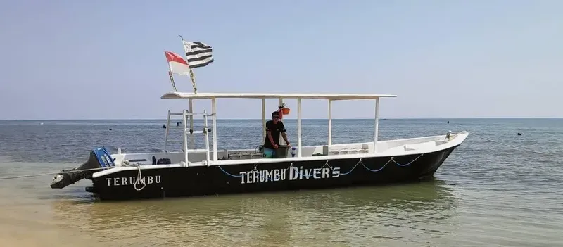 Bateau de plongée noir avec une personne à bord sur l'eau