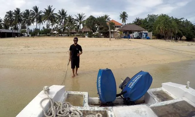 Homme marchant vers la mer avec deux moteurs hors-bord bleus