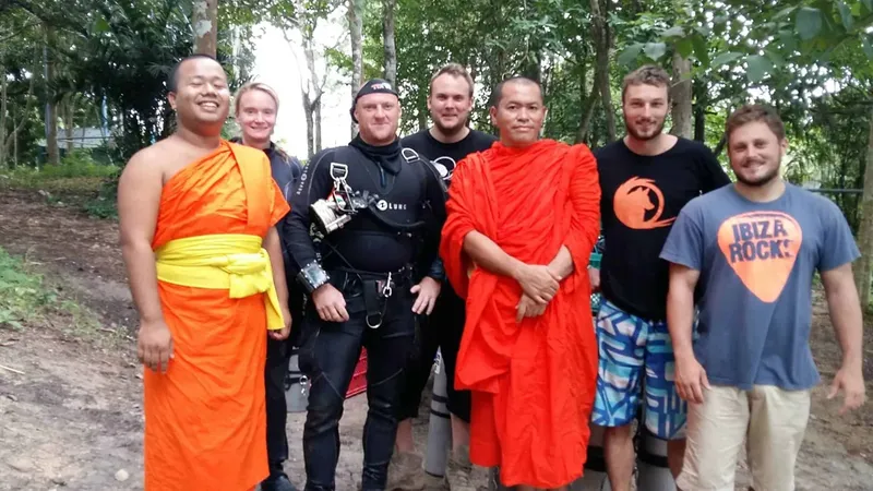 Groupe de personnes souriantes, certains en équipement de plongée, posent ensemble