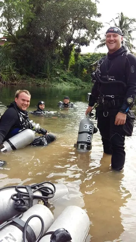 Plongeurs souriants dans l'eau avec bouteilles et équipement