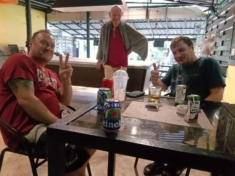 Trois hommes souriants assis à une table avec des boissons