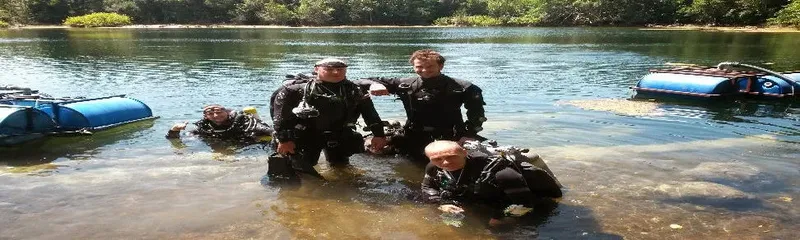 Plongeurs en combinaison sortant de l'eau avec leur équipement