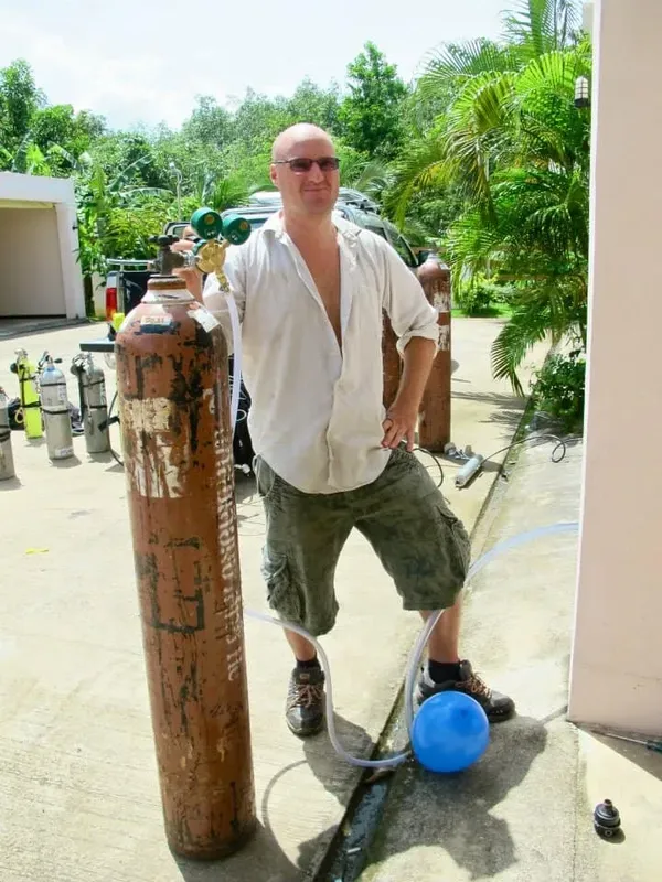 Un homme se tient debout près d'une bouteille de plongée rouillée