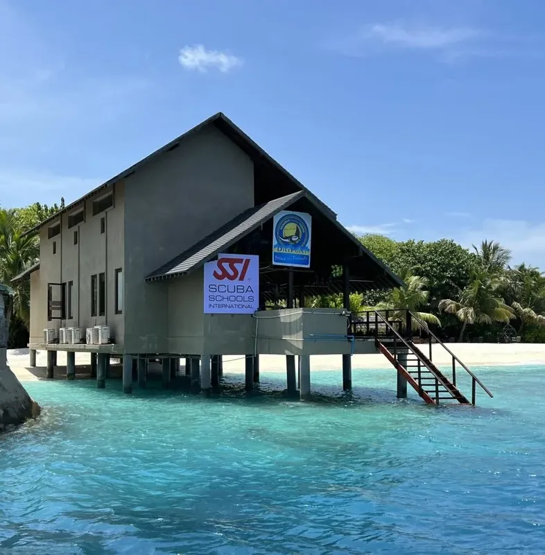 Bâtiment sur pilotis au bord de l'eau avec logo de centre de plongée
