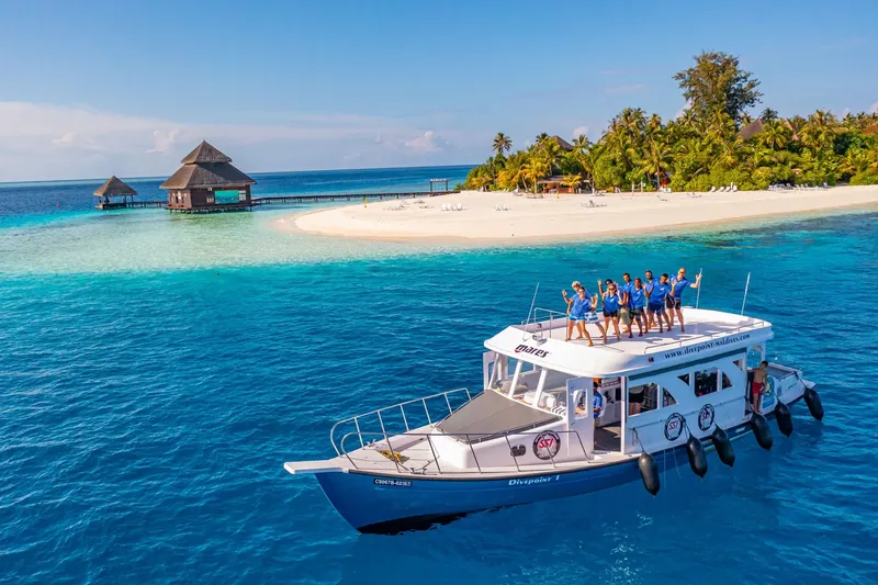 Bateau de plongée avec des personnes souriantes, île tropicale paradisiaque