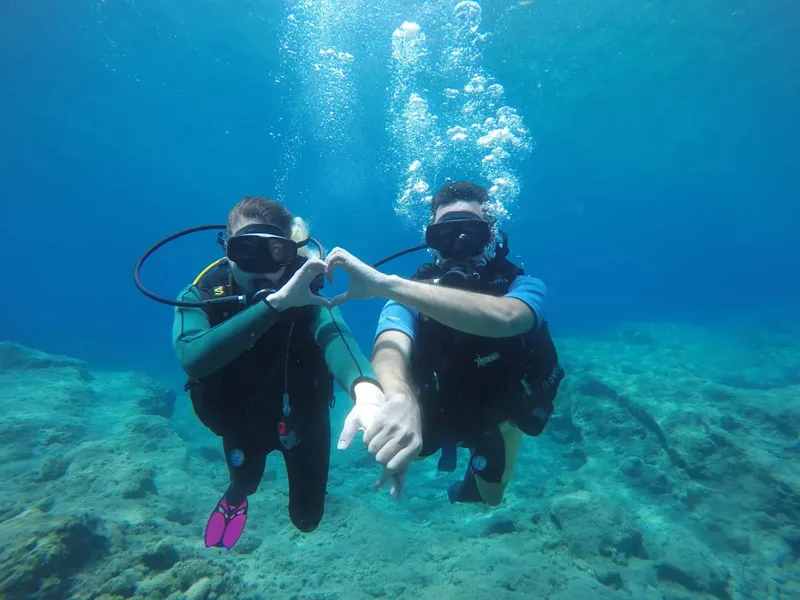 Deux plongeurs forment un cœur avec leurs mains sous l'eau