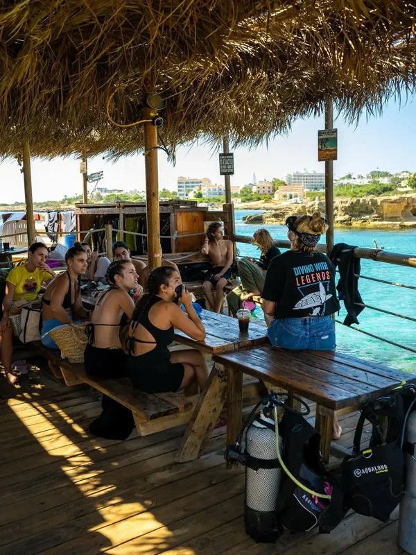 Groupe de personnes discutant sur une terrasse en bois près de la mer