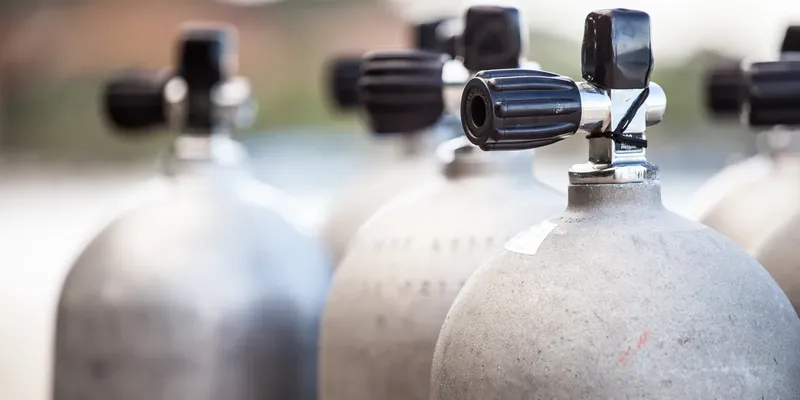 Bouteilles de plongée alignées avec robinets métalliques, équipement prêt à l'utilisation