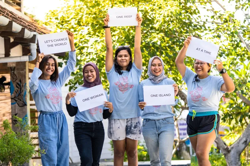 Cinq femmes souriantes tiennent des pancartes avec des messages écologiques