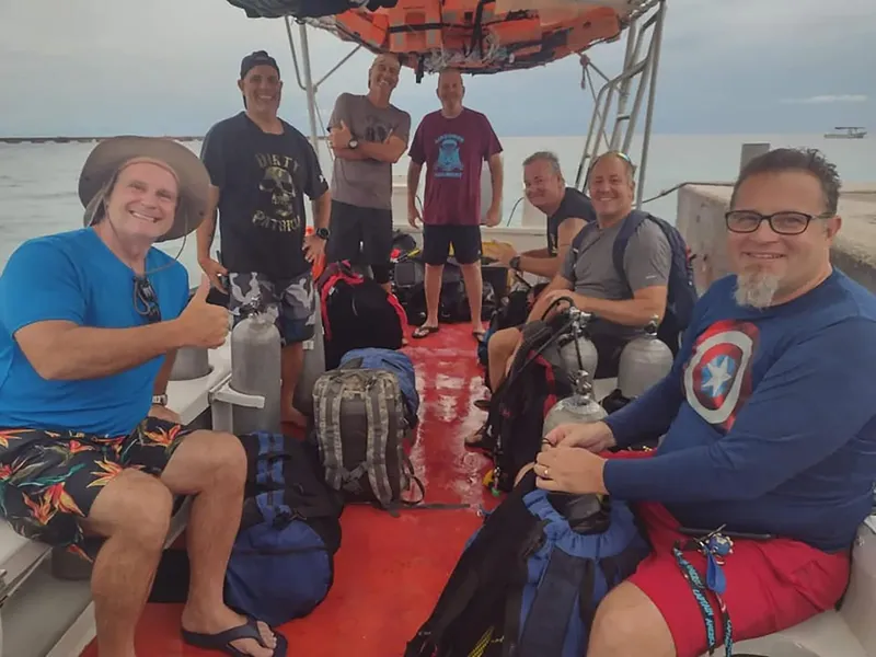 Groupe de plongeurs souriants sur un bateau avec leur équipement
