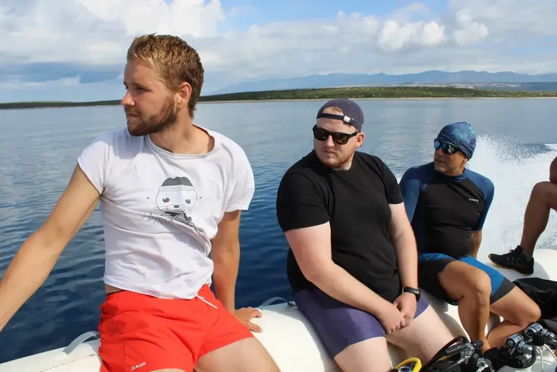Trois hommes à bord d'un bateau rapide en direction du site de plongée