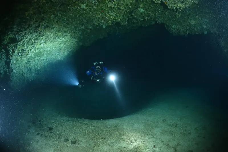 Plongeur explorant une grotte sous-marine avec une lumière puissante