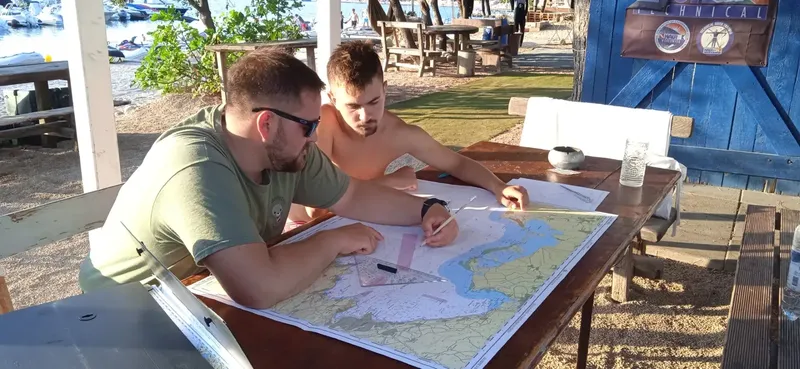 Deux hommes étudient une carte marine à l'extérieur d'un centre de plongée