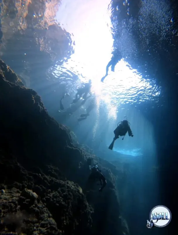 Plongeurs explorant une grotte sous-marine avec des rayons de lumière