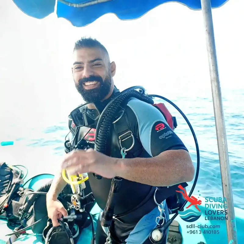 Plongeur souriant en combinaison, équipé, dans une eau claire et bleue