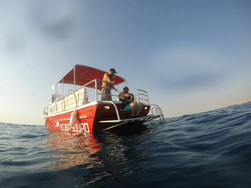 Bateau de plongée rouge avec deux personnes à bord sur l'eau