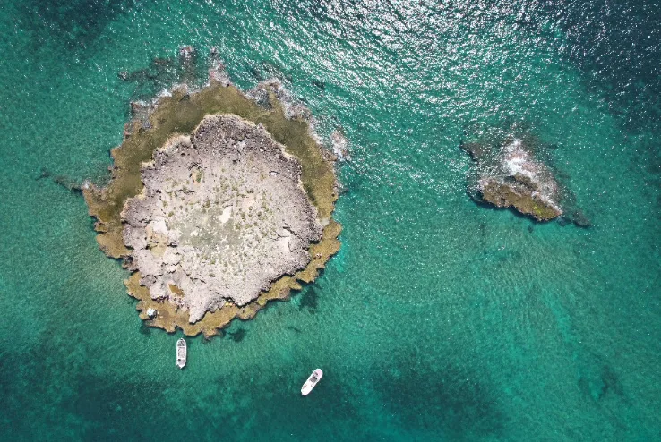 Vue aérienne d'îlots rocheux turquoise avec quelques bateaux de plaisance