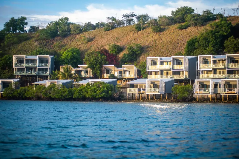 Maisons modernes sur pilotis au bord de l'eau, végétation luxuriante