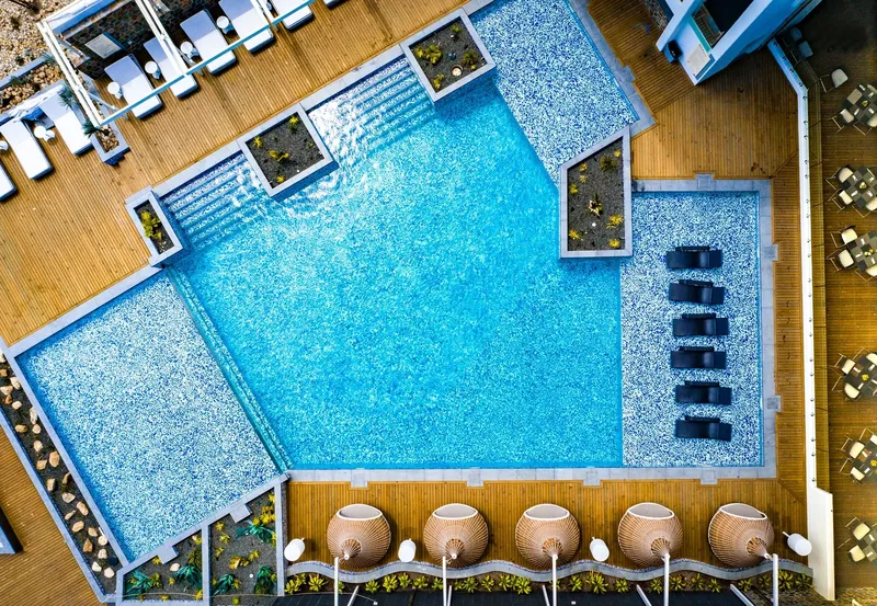 Vue aérienne d'une piscine rectangulaire avec des transats et végétation