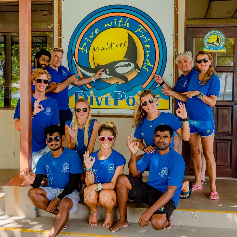 Groupe de personnes souriantes devant le centre de plongée aux Maldives