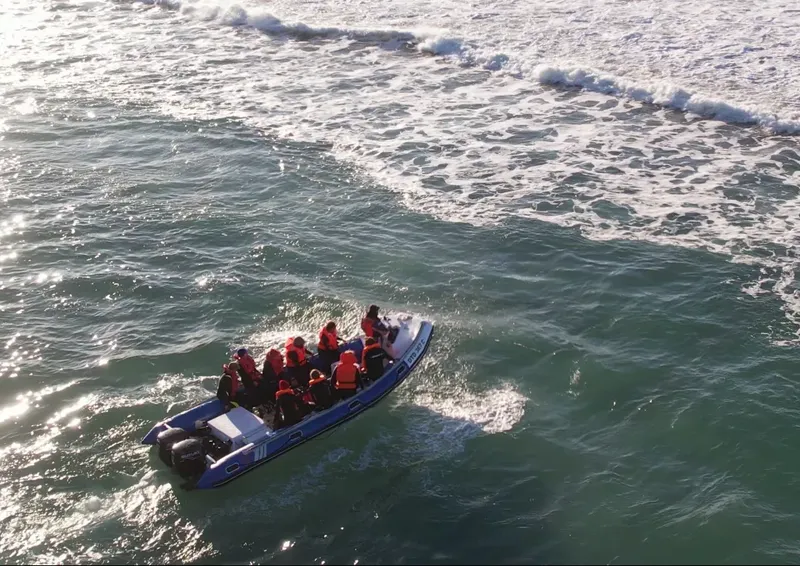 Un bateau semi-rigide transporte des plongeurs en mer, vêtus de gilets