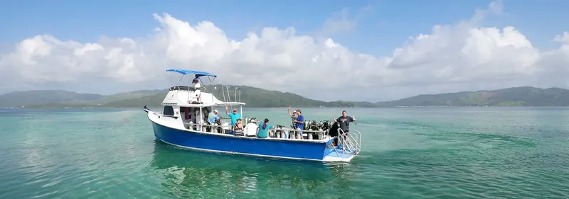 Bateau de plongée bleu avec des passagers en mer turquoise