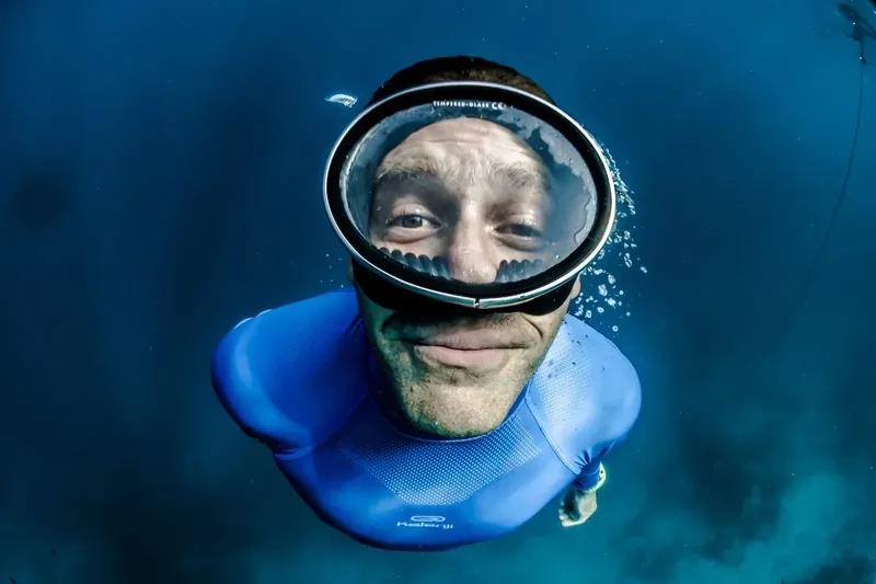 Plongeur souriant avec masque, vue sous-marine, lumière bleue, apnée