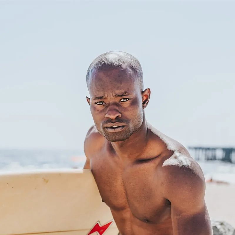 Homme torse nu regardant la caméra sur une plage ensoleillée