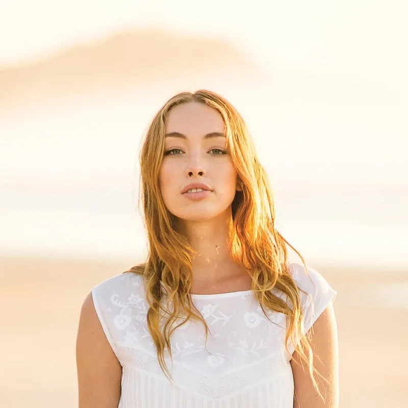 Jeune femme aux cheveux longs regardant la caméra sur plage