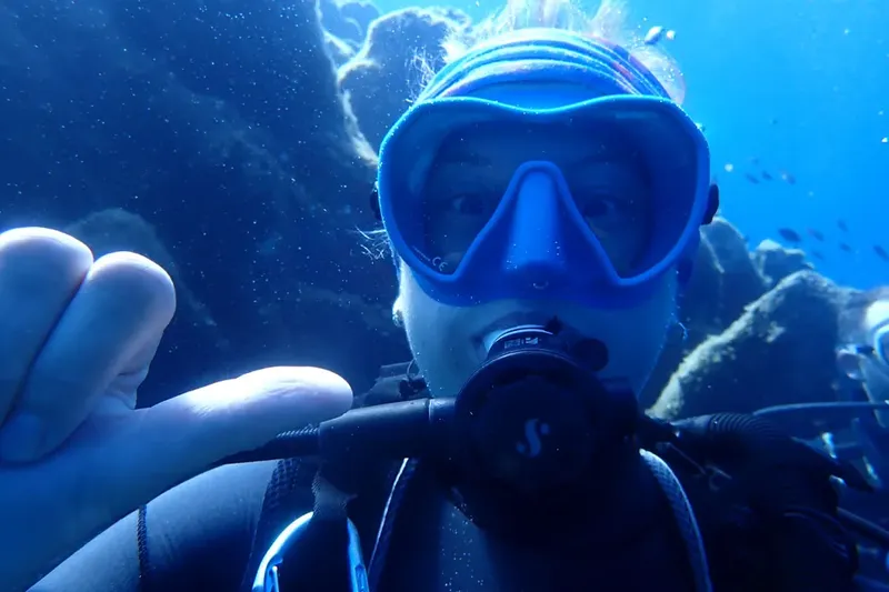 Plongeur souriant avec masque et détendeur dans l'eau bleue