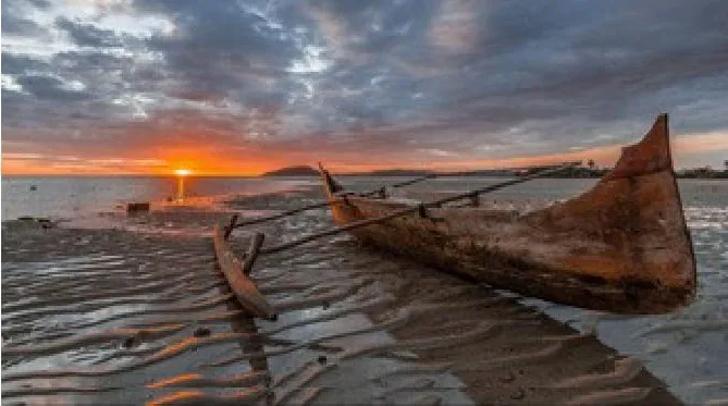 Bateau de pêche échoué sur une plage au coucher du soleil