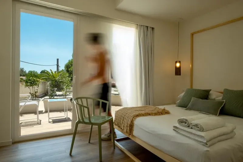Intérieur d'une chambre avec une personne floue entrant par une baie vitrée