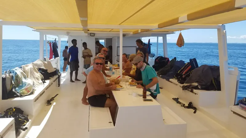 Plongée : groupe de personnes déjeune sur le pont d'un catamaran