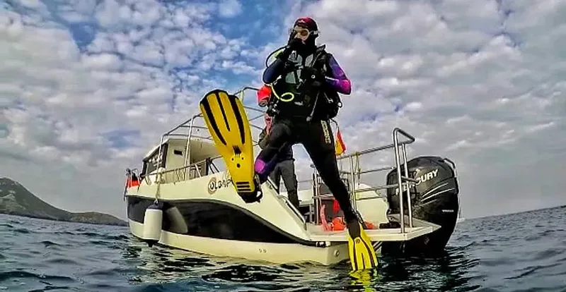 Plongeur équipé sur le point de plonger depuis un bateau blanc et noir