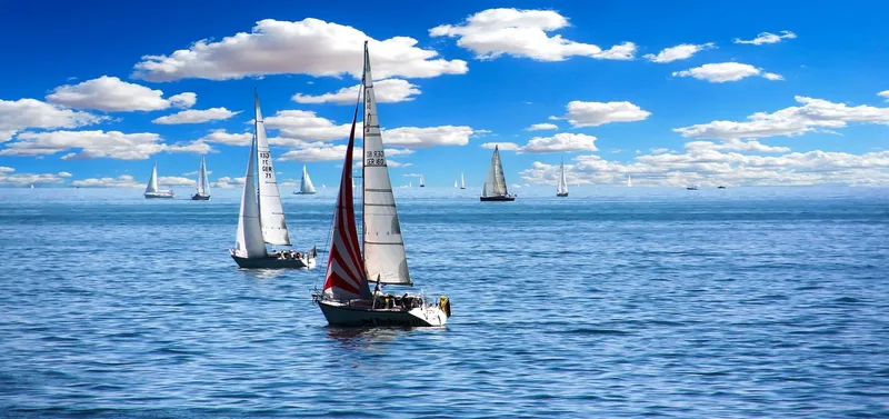 Voiliers sur mer bleue sous un ciel nuageux et ensoleillé