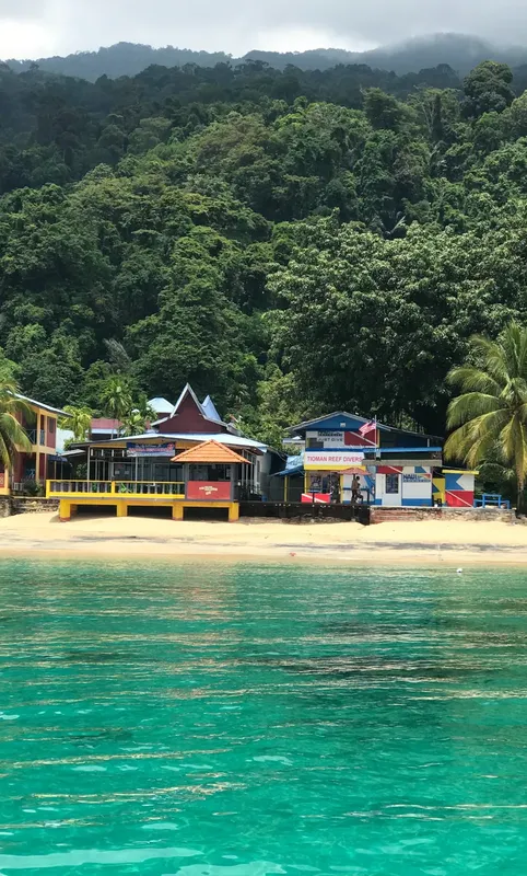 Bâtiments colorés sur une plage tropicale avec des personnes devant