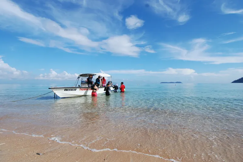 Plongée : un groupe de personnes équipées près d'un bateau sur une plage