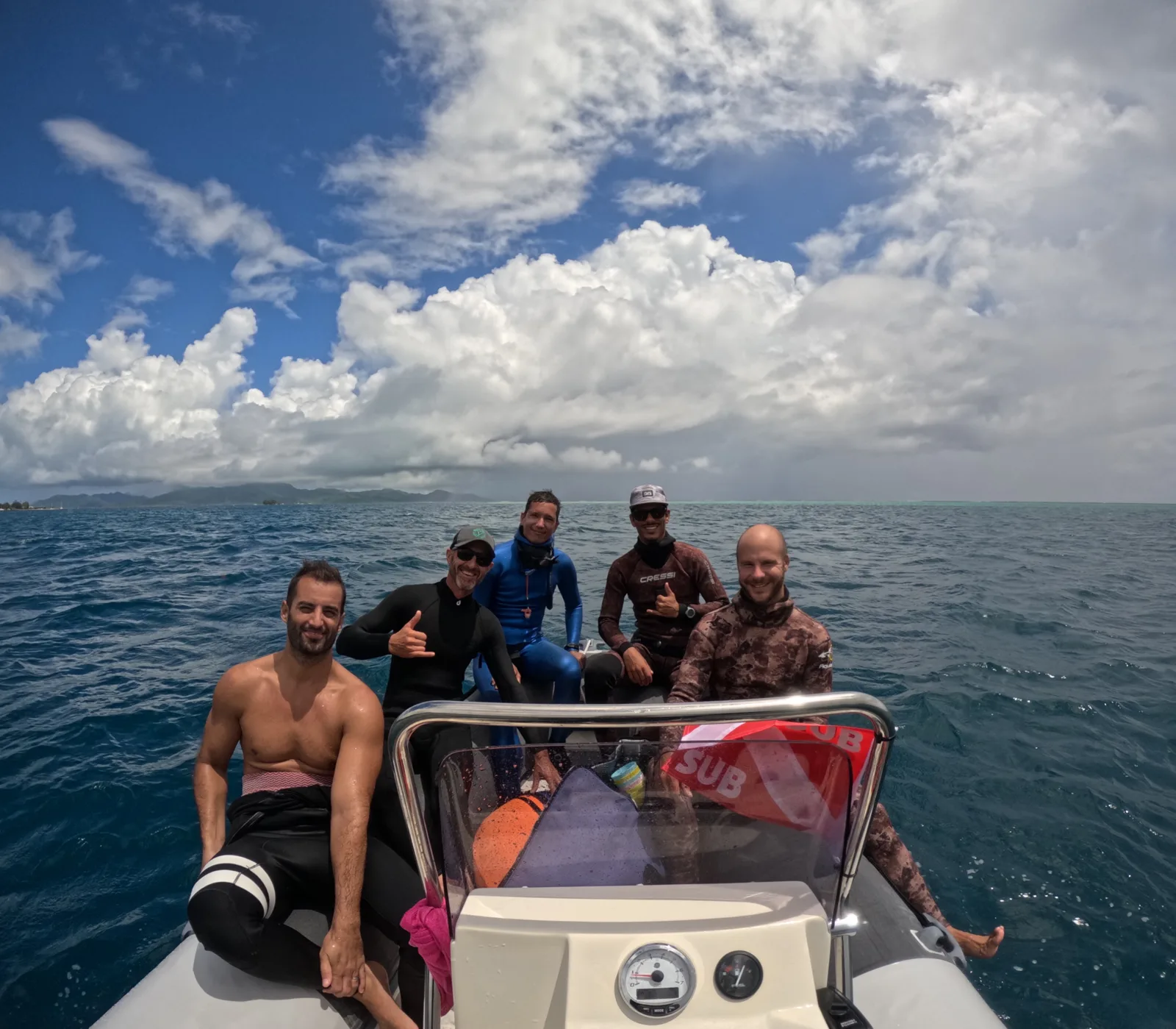 Groupe de plongeurs souriants sur un bateau en mer, ciel bleu