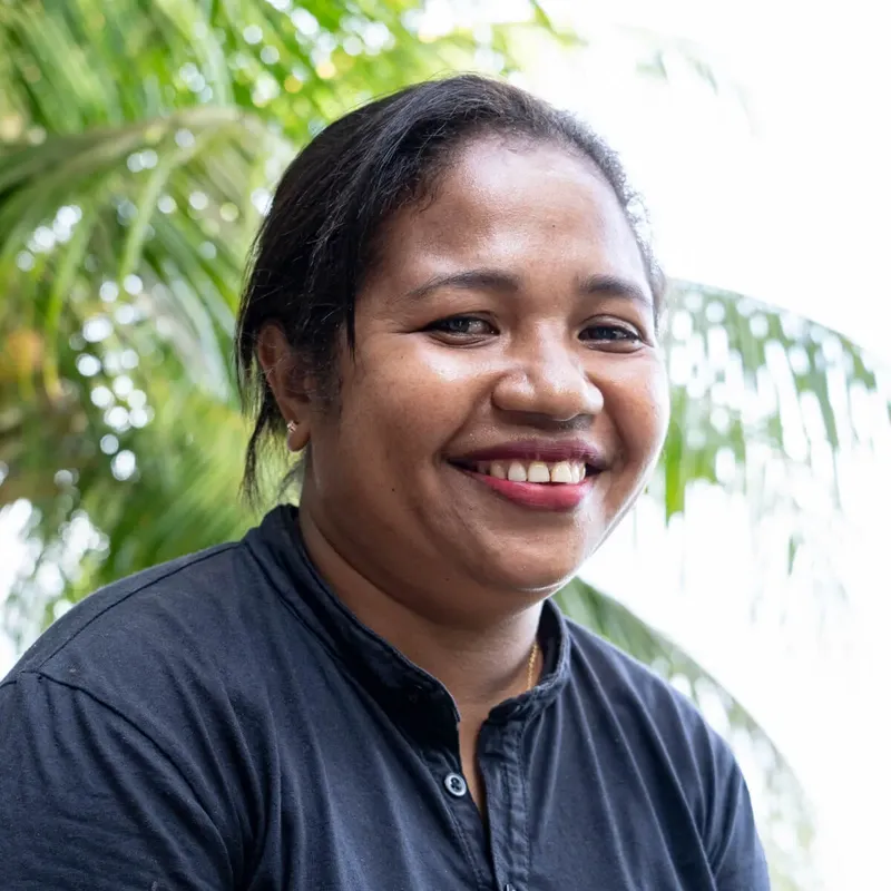 Portrait souriant d'une femme devant un flou de végétation tropicale
