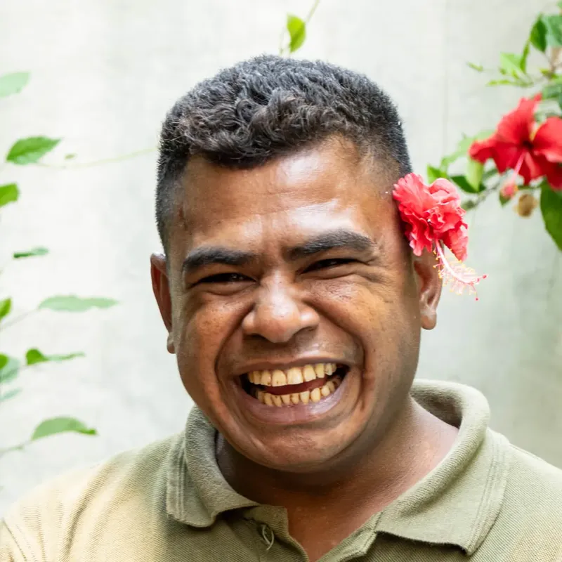 Homme souriant avec une fleur rouge dans les cheveux portrait