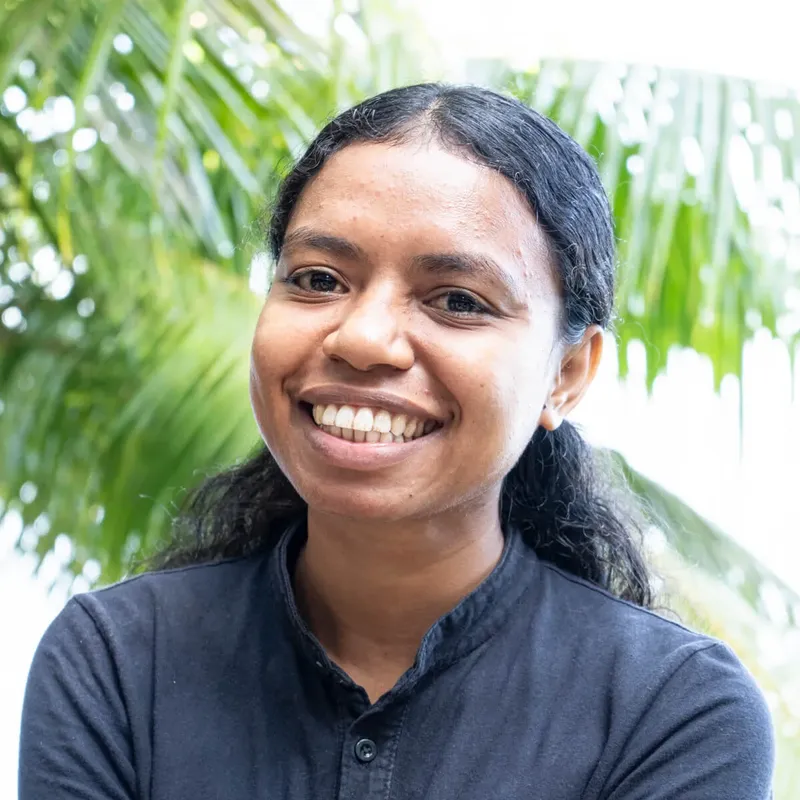 Portrait souriant d'une personne avec des cheveux foncés et un fond flou