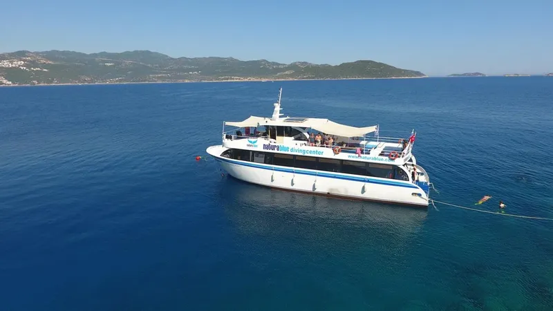 Bateau de plongée blanc et bleu en mer avec des plongeurs