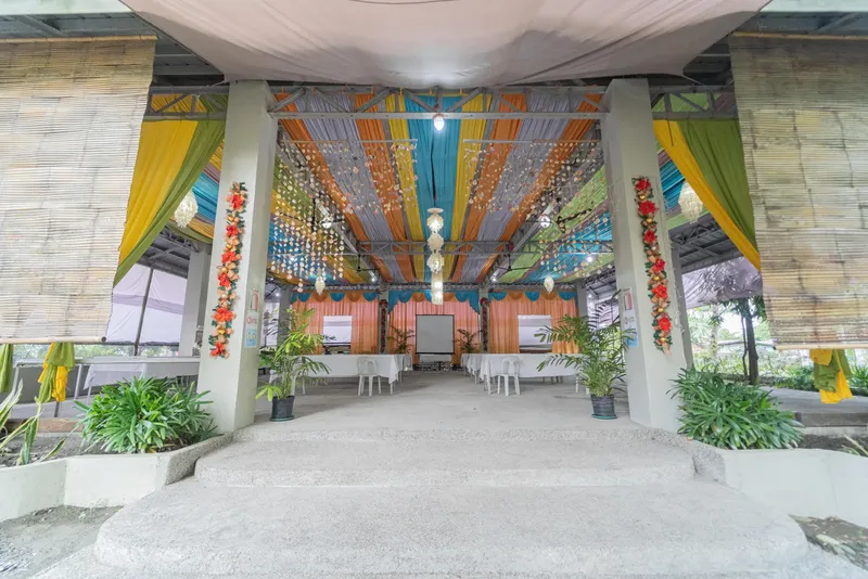 Espace de réception extérieur décoré avec des tissus colorés et plantes